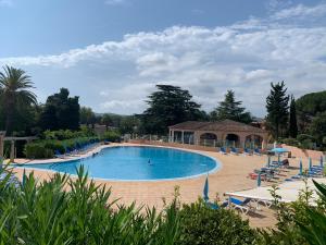 a large swimming pool with chairs and umbrellas at Appartement Grimaud bord de mer in Grimaud