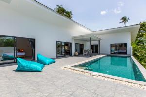 un patio trasero con piscina y una casa en Villa Nirvana, 3 Bedrooms, Chaweng Noi, en Koh Samui 