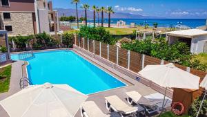 una piscina con sombrillas y la playa en Oliva Beach, en Máleme