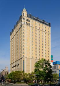 a large tan building with a sign on top of it at Hotel Monterey Sendai in Sendai