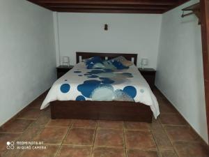 a bedroom with a bed with a blue and white comforter at Casa Rural El Pajar in El Pinar del Hierro