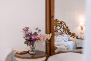um quarto com uma cama e um vaso de flores sobre uma mesa em B&B Toma Street em Lecce
