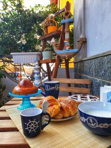 a wooden table with croissants and coffee cups on it at B&B Scilla Mare in Scilla