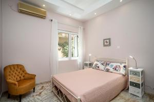 a bedroom with a bed and a chair and a window at Casa de Colores en Corfu! in Corfu Town