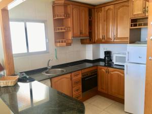 eine Küche mit Holzschränken und einem weißen Kühlschrank in der Unterkunft SUN and BEACH LOVERS 12019 in La Pineda