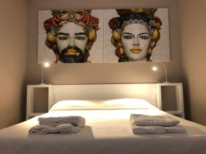 a bedroom with a bed with two portraits on the wall at Torre Venza in Valderice