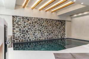 a swimming pool in a room with a stone wall at Korali Palace Hotel in Naxos Chora