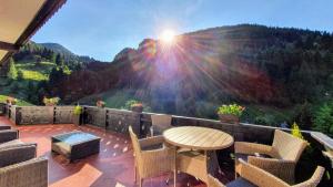 a patio with a table and chairs and the sun shining at Carpatica Lodge in Moieciu de Sus