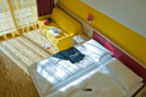 a small bedroom with a bed and a yellow headboard at Garda Sporting Club Hotel in Riva del Garda