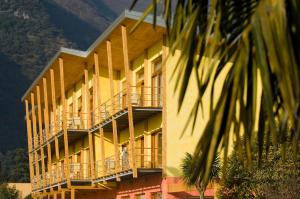 ein gelbes Gebäude mit Balkonen und einer Palme in der Unterkunft Garda Sporting Club Hotel in Riva del Garda