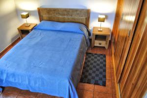 a bedroom with a bed with a blue comforter and two lamps at Casas Da Faja in Praia do Norte