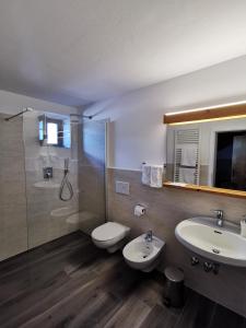 a bathroom with two sinks and a toilet and a shower at Hotel Eden Guesthouse in Marlengo