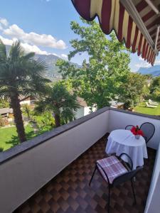 a balcony with a table and chairs and palm trees at Hotel Eden Guesthouse in Marlengo