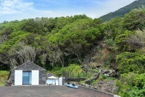 un pequeño edificio blanco con una colina al fondo en Casa dos Botes - WhaleBoat House TER, en São Caetano