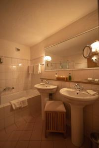 ein Badezimmer mit zwei Waschbecken, einer Badewanne und einem Spiegel in der Unterkunft Hotel Alpenrose mit Gourmet-Restaurant Azalée in Gstaad