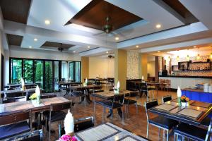 ein Esszimmer mit Tischen und Stühlen in einem Restaurant in der Unterkunft Baan Karon Resort in Karon Beach