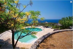 a swimming pool next to the ocean with a tree at Stone Cottages in Khalikerí