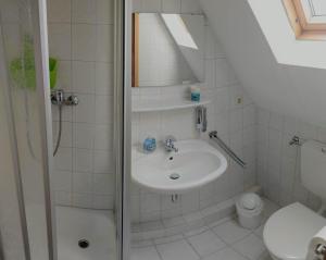 ein Bad mit einem Waschbecken, einer Dusche und einem WC in der Unterkunft Pension An der Reling in Dornumersiel
