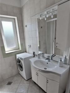 een badkamer met een wasmachine en een wastafel bij Apartments Aurora near beach in Medulin