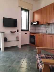 eine Küche mit Holzschränken und einem TV an der Wand in der Unterkunft Villa Bacino del Conte in Torre Colimena