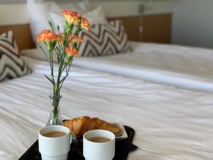 Una bandeja con dos tazas de café y un jarrón con flores. en Park Hotel Tornio, en Tornio