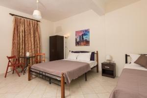 a bedroom with two beds and a table and a chair at Alekos Studios in Skala Potamias