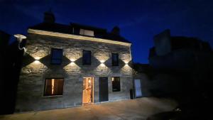 an old stone building with lights on it at night at La Petite Valise in Ploudalmézeau