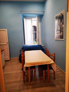 een tafel en stoelen in een kamer met een blauwe muur bij Casa Cupiello Via Chiaia - Casa Vacanze ad uso Esclusivo in Napels