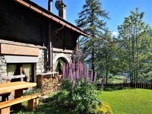 un edificio con flores púrpuras junto a un banco en MaisonGorret, en Valtournenche