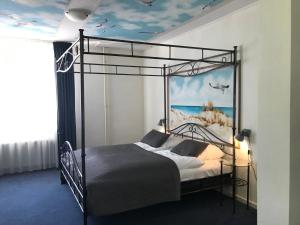 a bedroom with a canopy bed with a painting of the ocean at Fletcher Strandhotel Renesse in Renesse