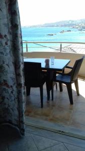 een tafel en stoel op een balkon met uitzicht op de oceaan bij Captain Nick in Chania