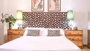 ein Schlafzimmer mit einem weißen Bett mit zwei Kommoden und zwei Lampen in der Unterkunft BizFlats Garden House in Barcelona