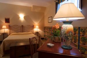 ein Schlafzimmer mit einem Bett und einem Tisch mit einer Lampe in der Unterkunft Agriturismo Baglio Vecchio in Castelvetrano Selinunte