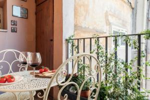 a table and chairs on a balcony with wine glasses at Domus Quiritum Charming, Appartamento d'Epoca a Campo de' Fiori in Rome
