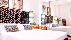ein weißes Schlafzimmer mit einem Bett und einem Spiegel in der Unterkunft BizFlats Garden House in Barcelona