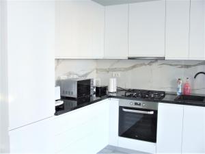 a kitchen with white cabinets and a stove top oven at ALEXYS TOP RESIDENCE in Mamaia Sat/Năvodari