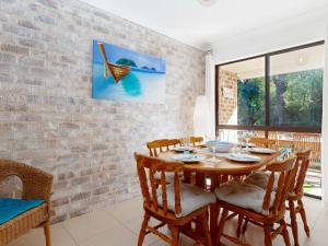 una sala da pranzo con tavolo e sedie in legno di Bay Parklands, 54 2 Gowrie Avenue - air con, wifi, pool, tennis court,child friendly a Nelson Bay