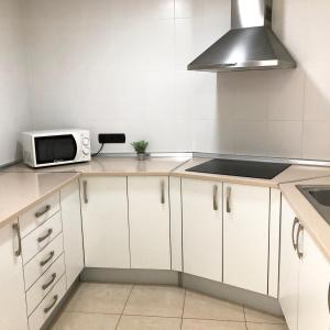 a kitchen with white cabinets and a microwave at Cotillo Ocean View in El Cotillo