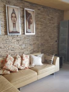 a living room with a couch with three pictures on a brick wall at Appartamento moderno in Le Castella