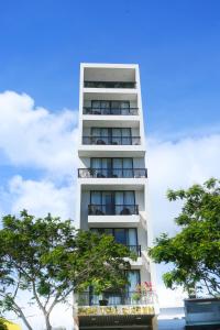 een hoog wit gebouw met bomen ervoor bij Son Tra Green Hotel & Apartment in Da Nang