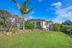 ein Haus mit einer Palme im Hof in der Unterkunft Beachy Bach - Mangawhai Heads Holiday Home in Mangawhai