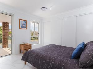 a bedroom with a bed with blue pillows at 5 Bent Street - huge house with Foxtel & Aircon in Fingal Bay