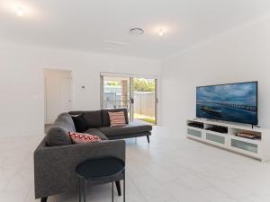a living room with a couch and a flat screen tv at 5 Bent Street - huge house with Foxtel & Aircon in Fingal Bay