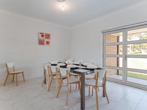 a white dining room with a black table and chairs at 5 Bent Street - huge house with Foxtel & Aircon in Fingal Bay
