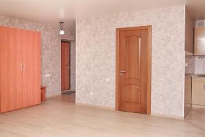 チュメニにあるApartments Maxima Gorkogoの木製のドアとキッチンが備わる空き部屋