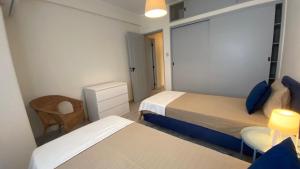 Un dormitorio pequeño con dos camas y una silla. en Lusitania T2 Frente Mar em Quarteira, en Quarteira