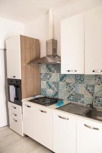 a kitchen with white cabinets and a stove top oven at Bilocale sul lungomare di Forio d'Ischia - Serpico sea & more in Ischia