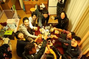 a group of people sitting around a table drinking wine at Goto Guest House Utojuku in Goto