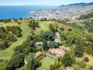 una vista aerea di una casa su una collina vicino all'oceano di Casa Velha do Palheiro Relais & Chateaux a Funchal