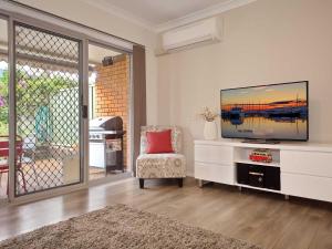 a living room with a flat screen tv and a chair at Bushmans, 9 24 Tomaree Street - Spacious townhouse with air conditioning and close to Nelson Bay Town Centre in Nelson Bay